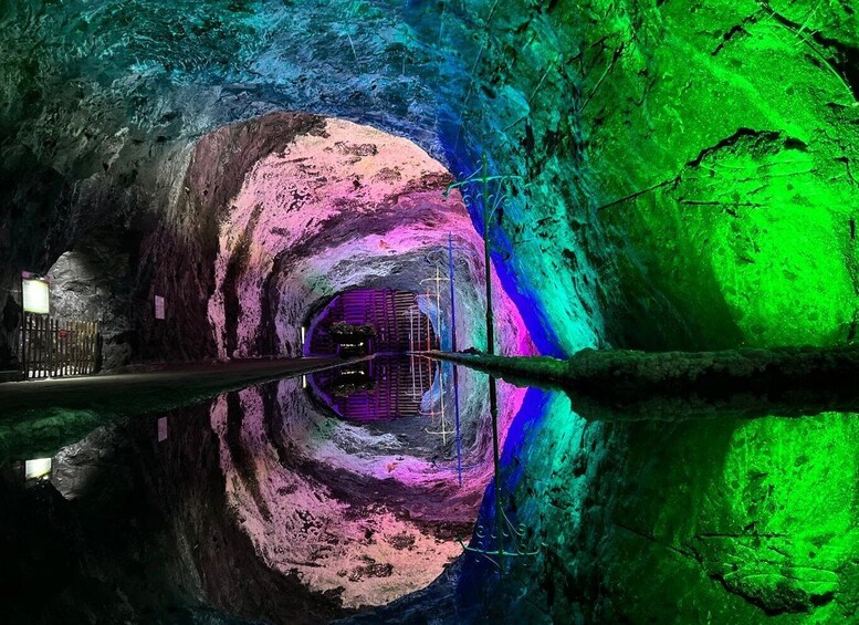 A cave with colorful lighting and a reflective water surface. 5