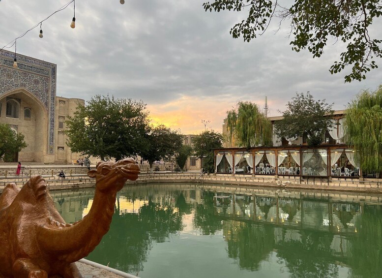 A historic building with intricate tile work, a reflective pool, and a restaurant with outdoor seating. 1