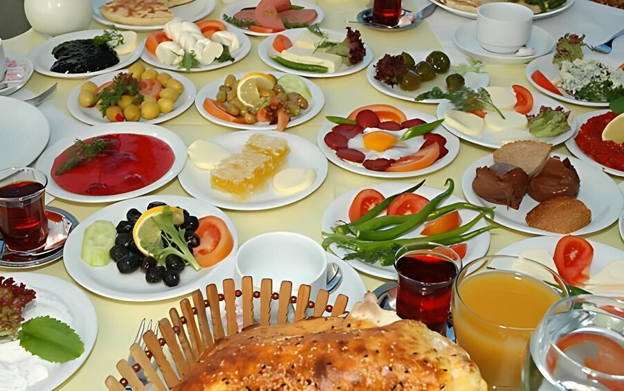 A table with various dishes, including salads, meats, and bread, along with drinks and utensils. 2