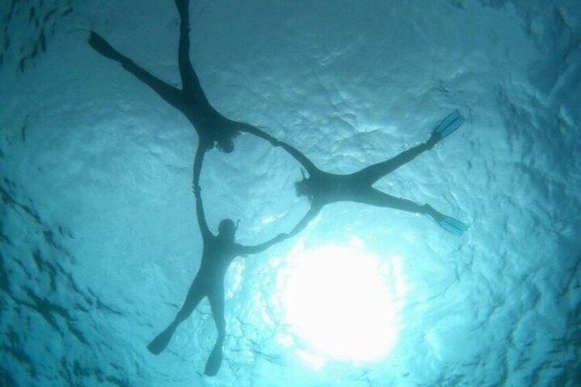 Two people scuba diving in a cave with sunlight filtering through. 3