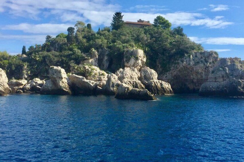 A rocky coastline with a building on top, surrounded by clear blue water. 5