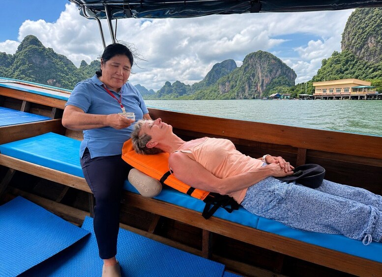 A person lying on a boat with a mountainous landscape in the background. 1