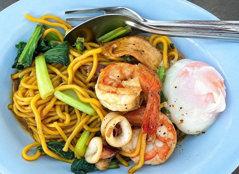 A plate of stir-fried noodles with shrimp, mushrooms, bok choy, and a poached egg. 2