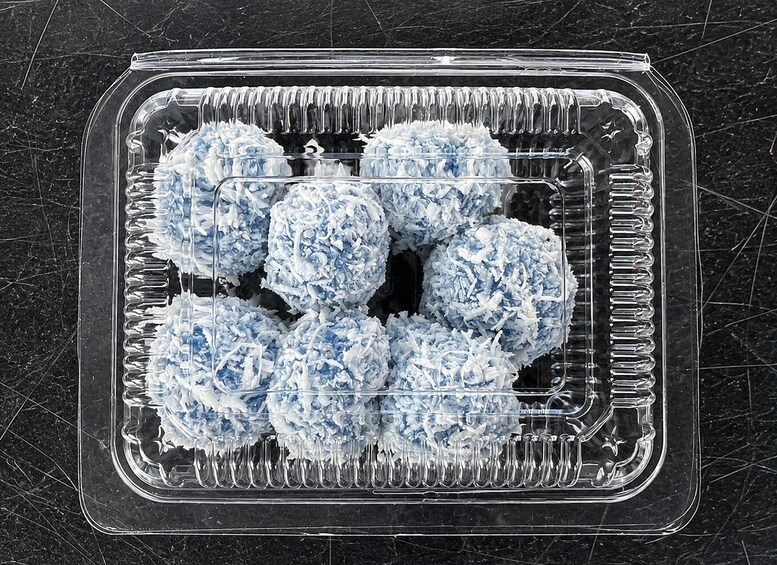 A clear plastic container with blue and white spherical objects, possibly food items, on a dark surface. 3