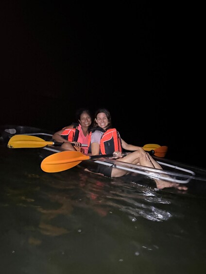 Two people in a kayak on a body of water at night. 2
