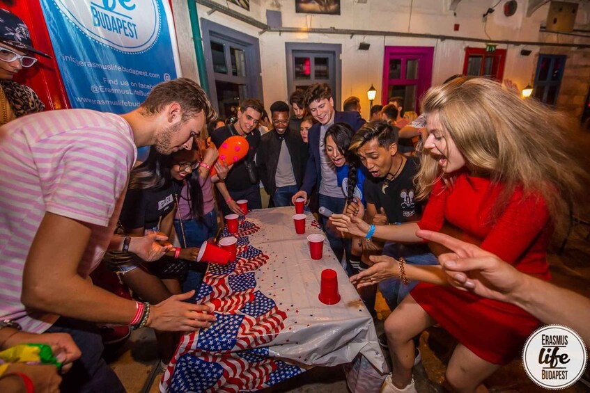 A group of people gathered around a table with American flag decorations and red plastic cups. 3