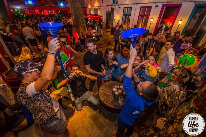 A crowded outdoor social gathering with people holding umbrellas and balloons. 4