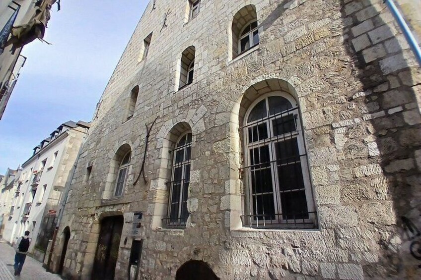 A stone building with arched windows and a person walking on the sidewalk. 2
