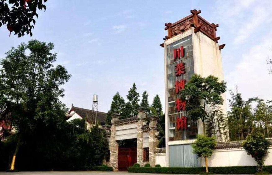 A traditional building with a red sign, surrounded by trees and a stone structure. 3