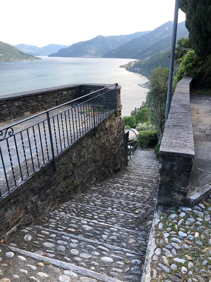 A stone staircase leading to a stone railing overlooking a lake with mountains in the distance. 3