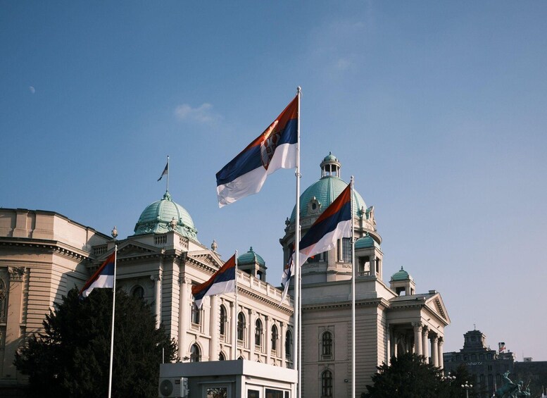 A large building with domed roofs and multiple flags, including the national flag. 1