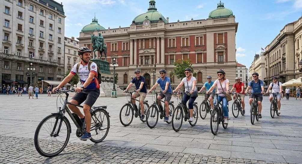 A group of cyclists in a public square with historic buildings in the background. 4