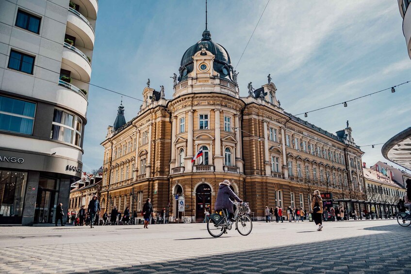 A historic building with a dome and statues, surrounded by pedestrians and cyclists. 1