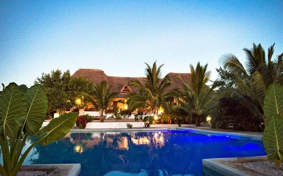 A swimming pool surrounded by palm trees and a building with a red roof. 3