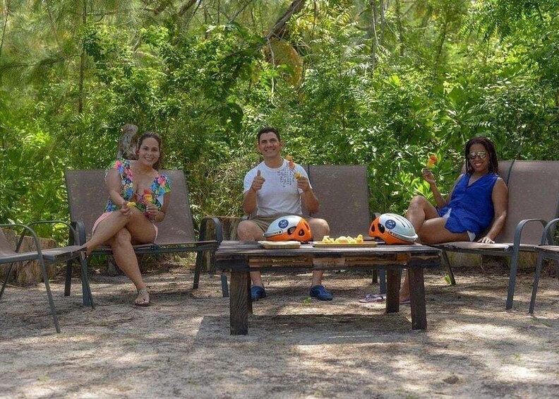 Three people sitting on benches outdoors with a table between them. 4