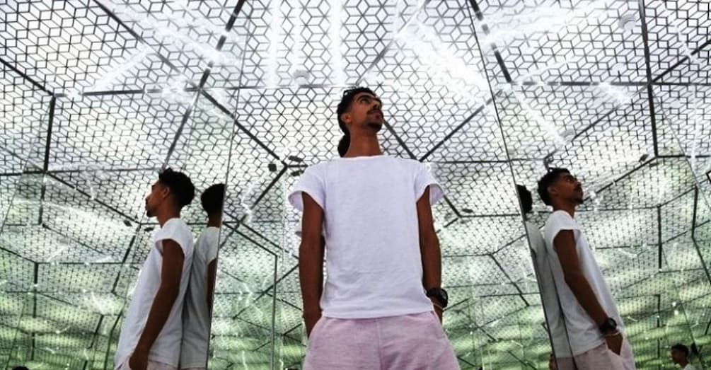 A person standing in front of a geometric metal structure. 3