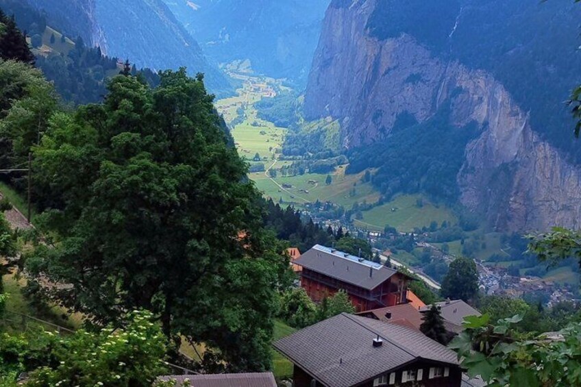 A valley with houses, a large tree, and mountains in the background. 2