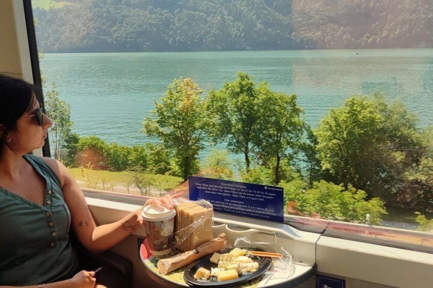 A person seated by a window overlooking a lake with trees and a signboard. 4