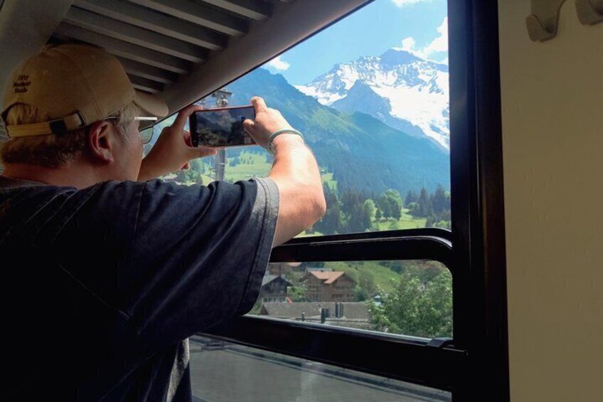 A person taking a photo of a mountain landscape through a window. 3