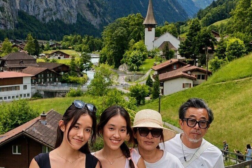 A group of people standing on a hill overlooking a village with a church and houses. 5