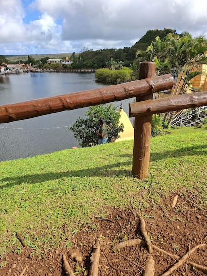 A wooden fence, grassy area, and a body of water with a hill in the background. 3