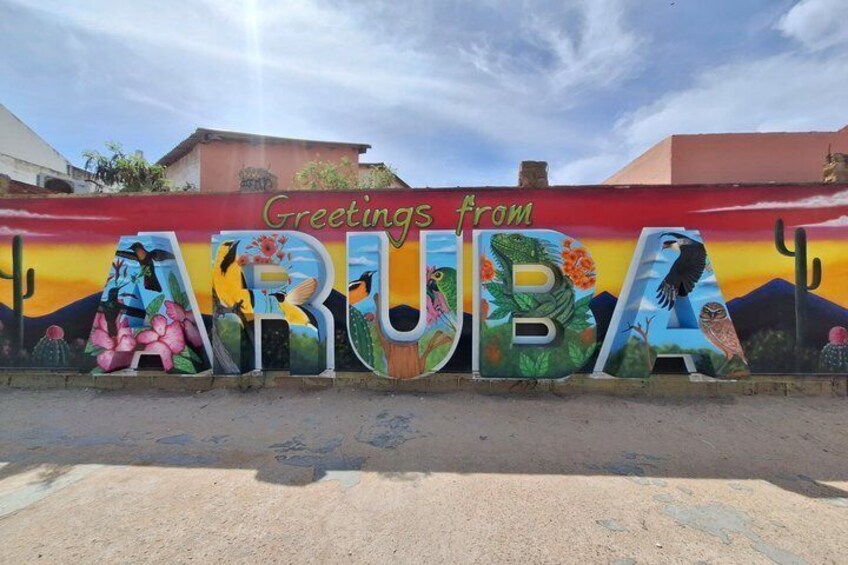A colorful mural with the word 'ARUBA' and 'Greetings from' on a wall. 4