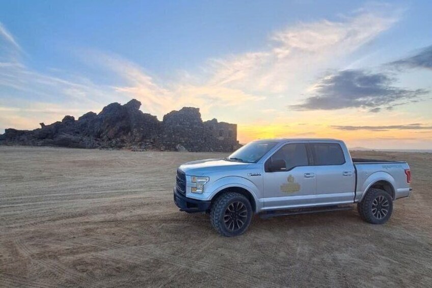 A white pickup truck parked in a desert with rocky formations in the background. 5