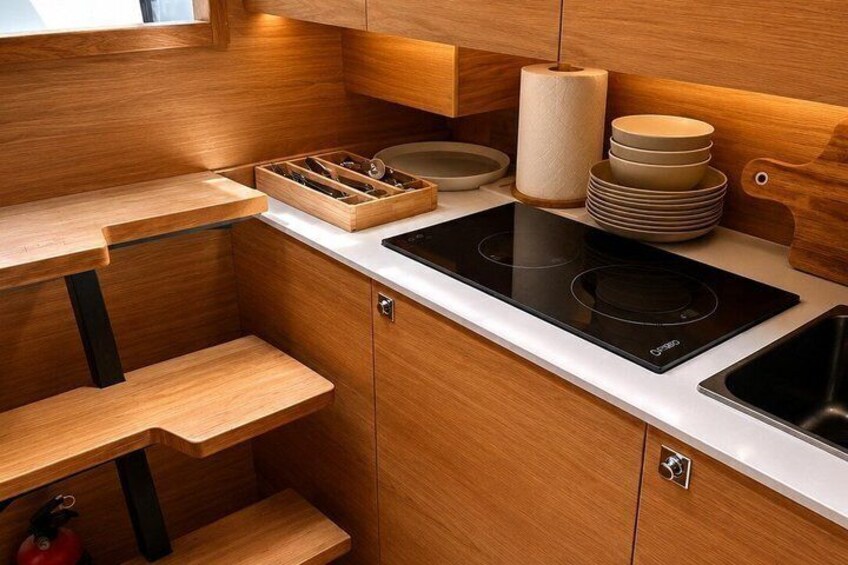 A modern kitchen with wooden cabinetry, a black induction cooktop, and a stainless steel sink. 3