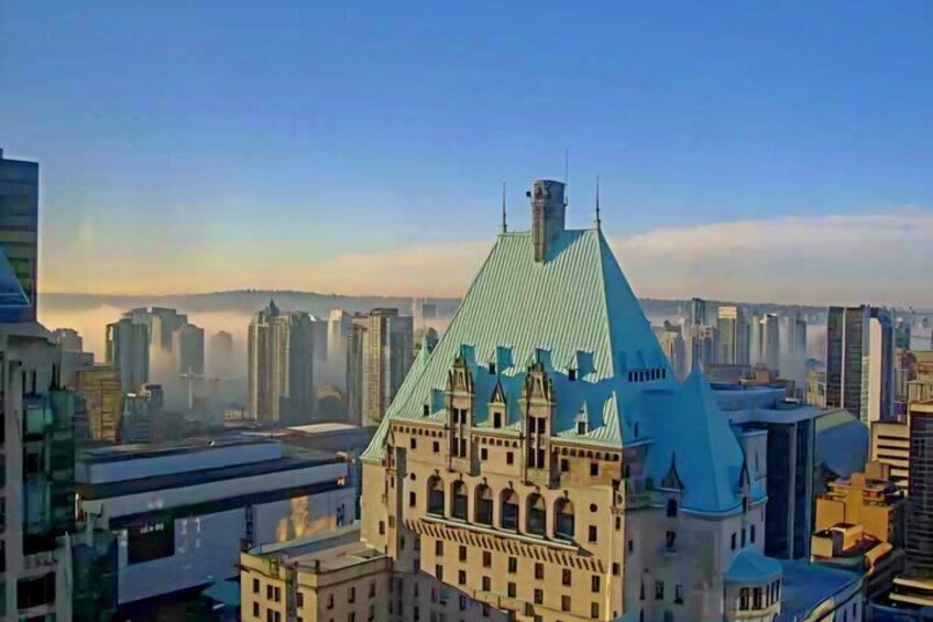 A cityscape with a prominent building featuring a steep, blue roof and arched windows. 4