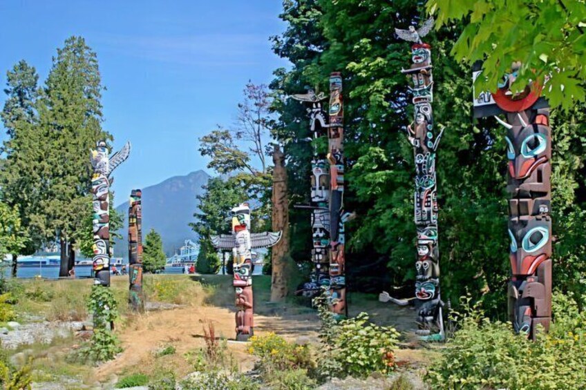 Totem poles in a forested area with a mountain in the background. 5