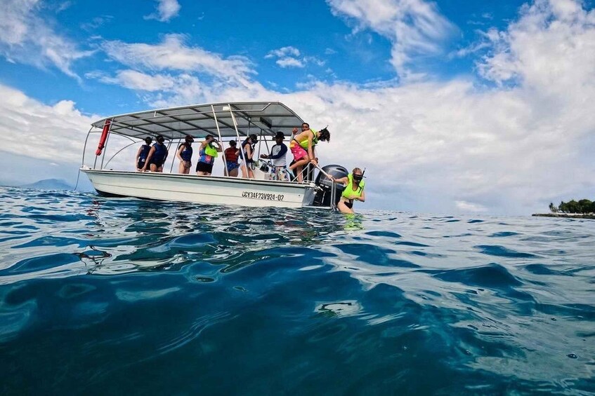A boat with people on board, floating on clear blue water. 1