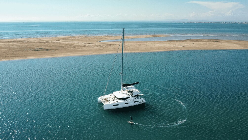 A sailboat anchored near a sandy beach with calm waters. 2