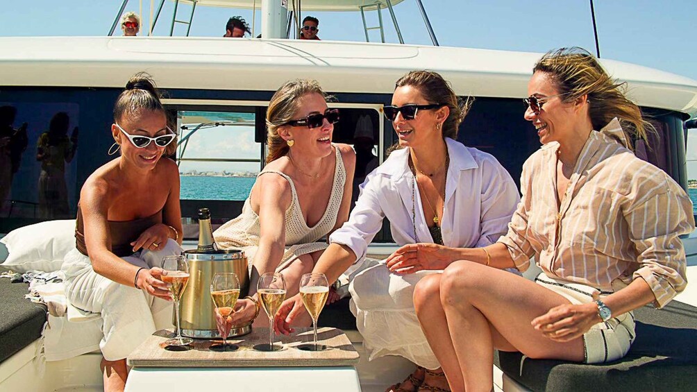 A group of people on a boat with a bottle of champagne and glasses. 1