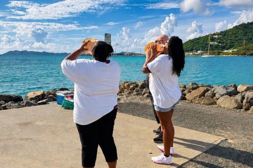 Two people taking a photo, a rocky shoreline, and a body of water. 1