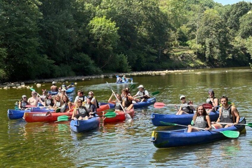 People in canoes on a calm river surrounded by trees. 3