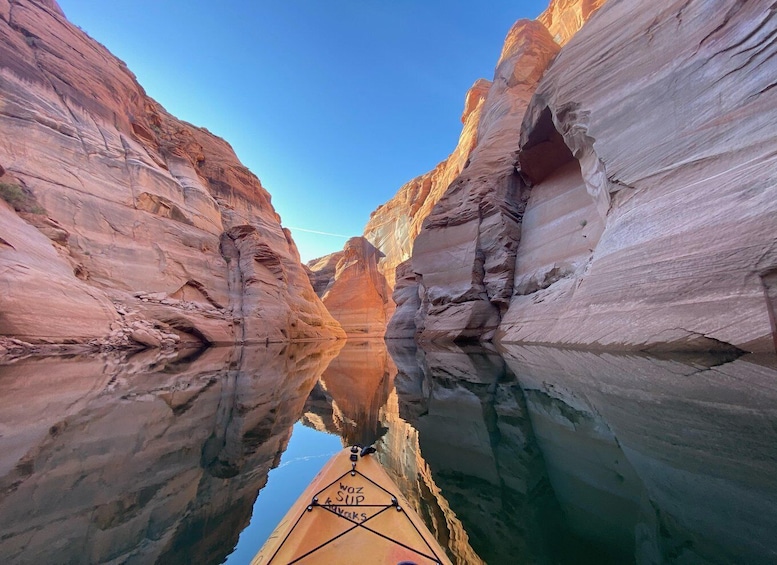 A kayaker in a narrow canyon with rock walls reflecting in the water. 2