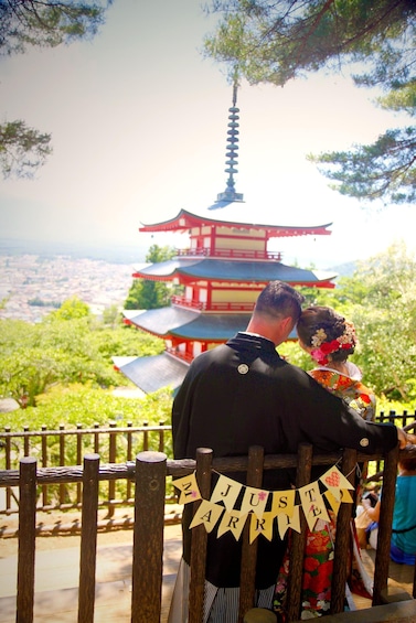 A couple overlooking a pagoda with a banner reading 'JUST MARLY' in a park. 1