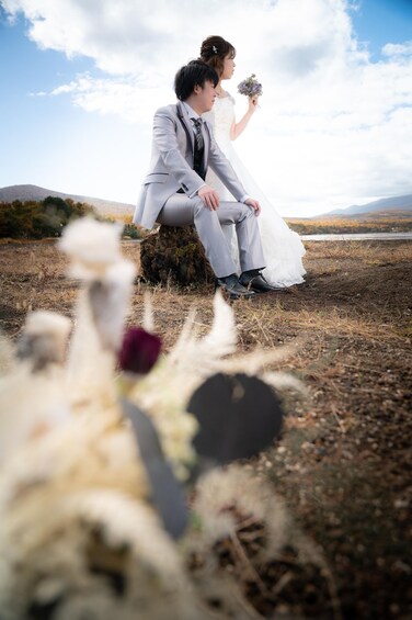 A couple sitting on a rock with a lake and mountains in the background. 4