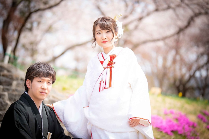 A person in traditional attire standing in a garden with cherry blossoms. 5