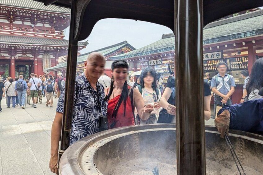 A group of people standing in front of a traditional building with a large circular structure emitting steam. 5