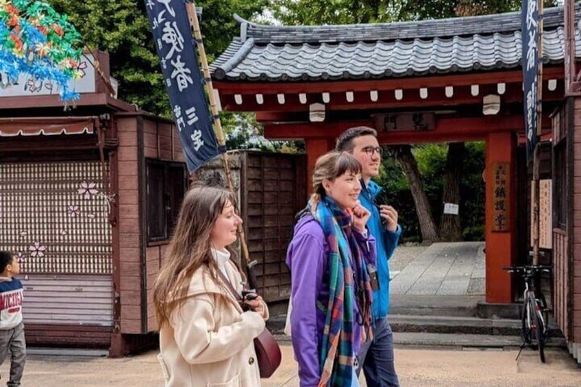A traditional Japanese gate with a red torii, a person in a white coat, and another in a blue jacket. 5