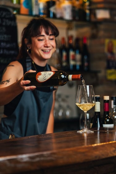 A person pouring a drink from a bottle into a glass. 1