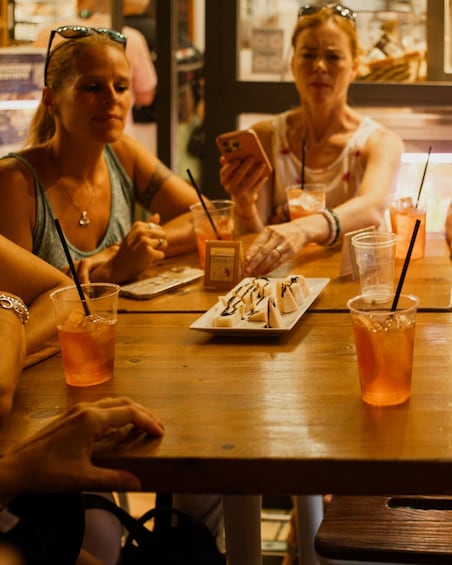 Two women sitting at a wooden table with drinks and a dessert plate. 5