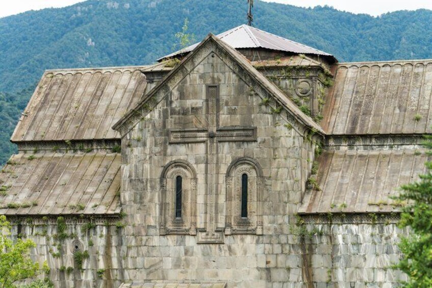 A stone church with a cross, arched windows, and a mountain backdrop. 3