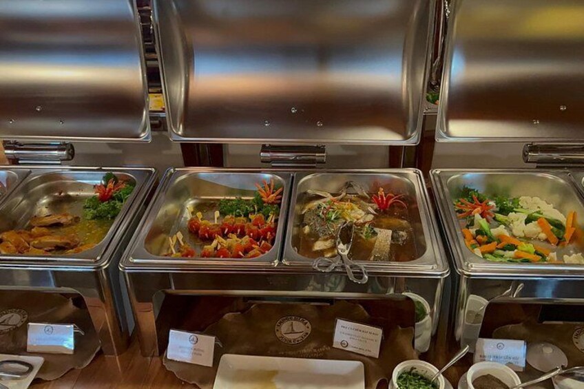 A buffet with various food items in metal containers, some with garnishes. 2