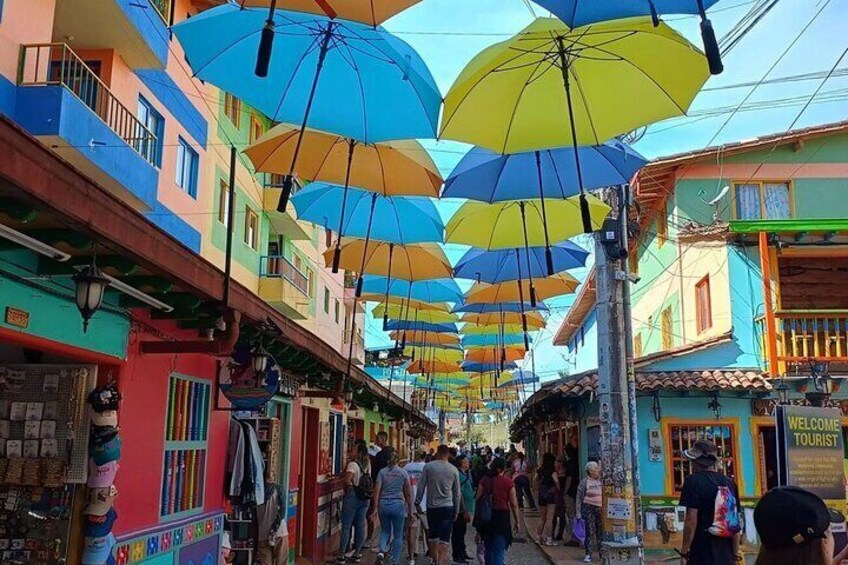 A colorful street with people walking, covered by umbrellas. 5