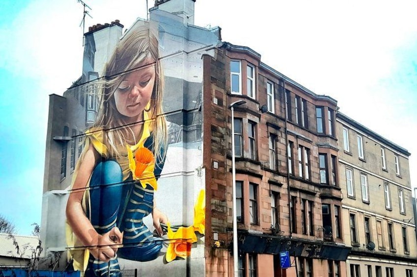 A mural of a woman holding a yellow flower on a building. 3
