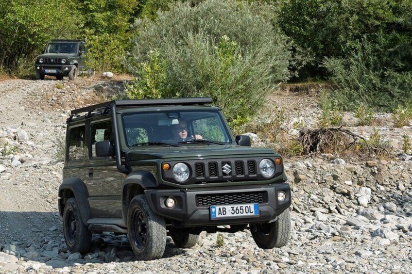 A dark green off-road vehicle on a rocky path with sparse vegetation. 4