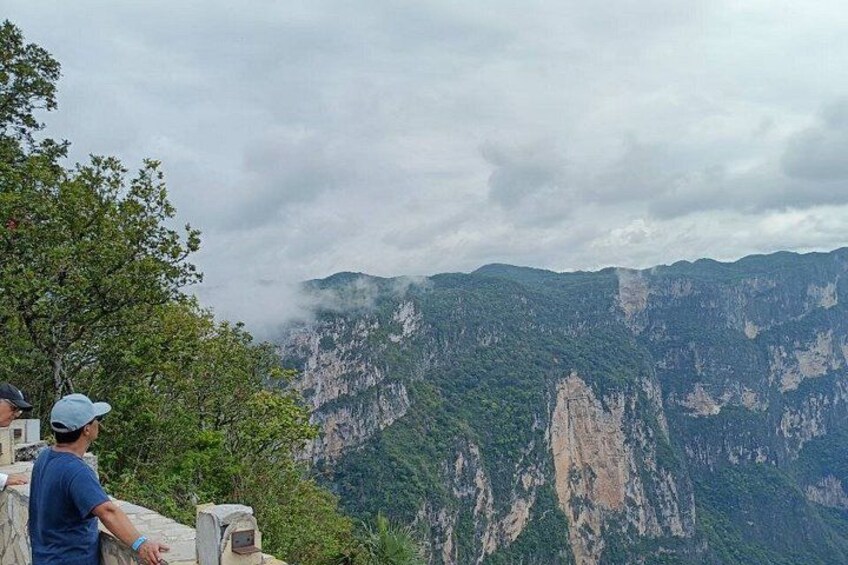 A mountainous landscape with a person standing on a ledge overlooking the valley. 2