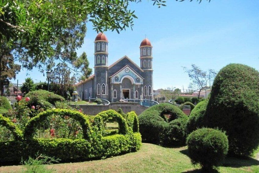 A church with two towers, surrounded by well-manicured hedges and a clear blue sky. 5